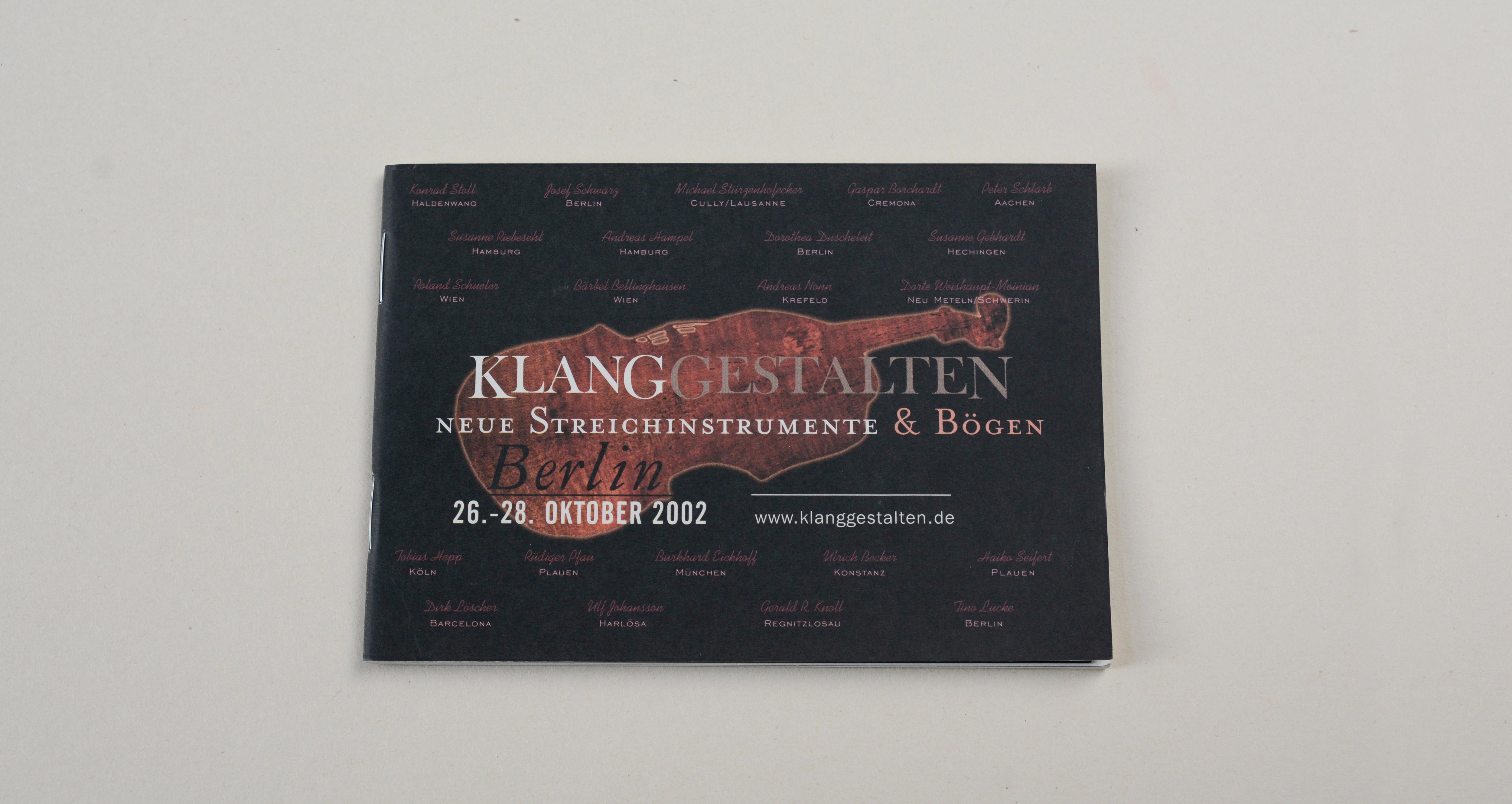 Cover catalogue landscape format. Black background. Large silhouette of violin in the middle. Large logo/title and line of text overlayed. Several signatures overlayed on entire cover.