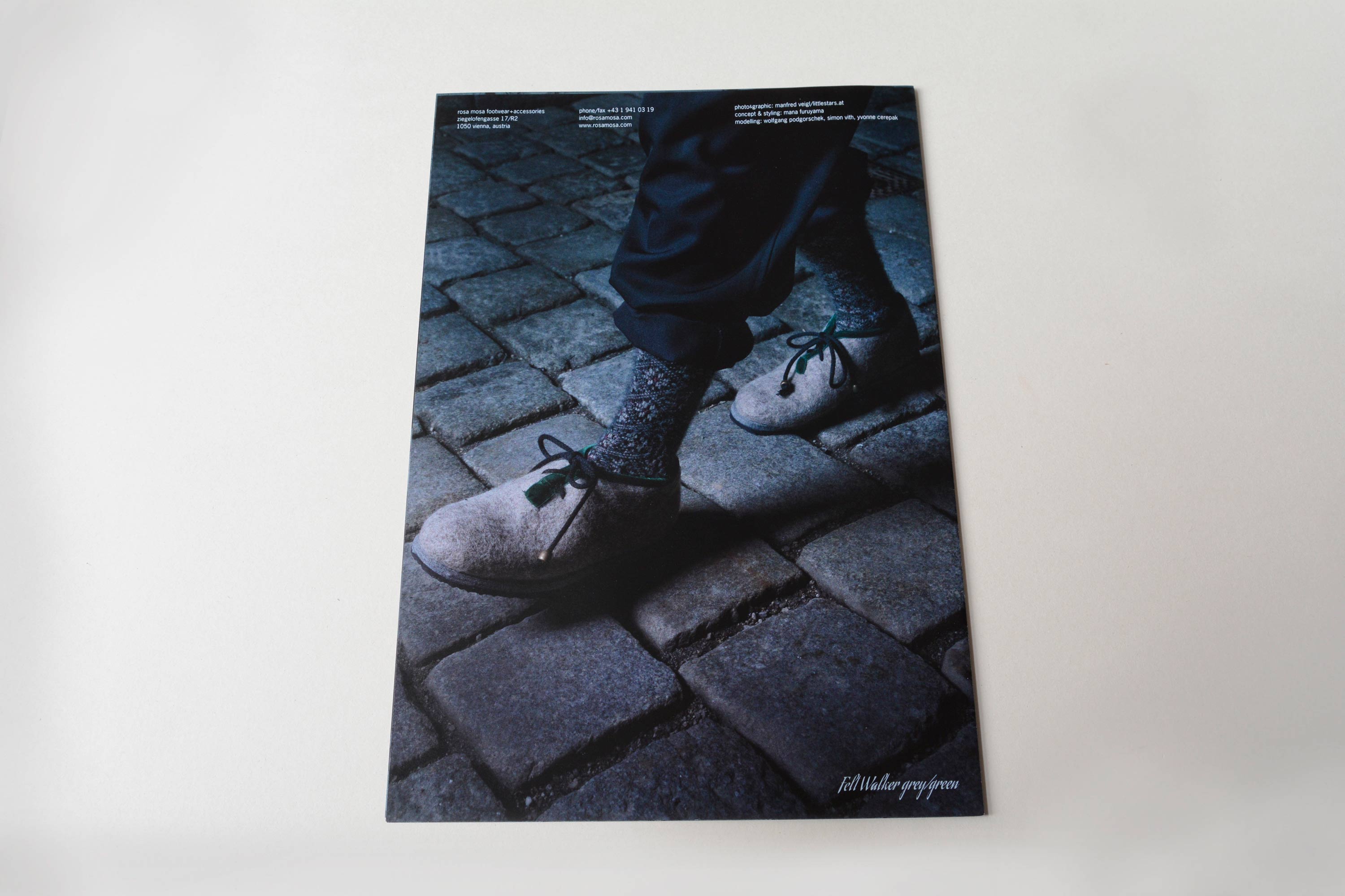 Back catalogue. Full-page close-up photo of feet in shoes walking on coblestone. Small text blocks overlayed at top.
