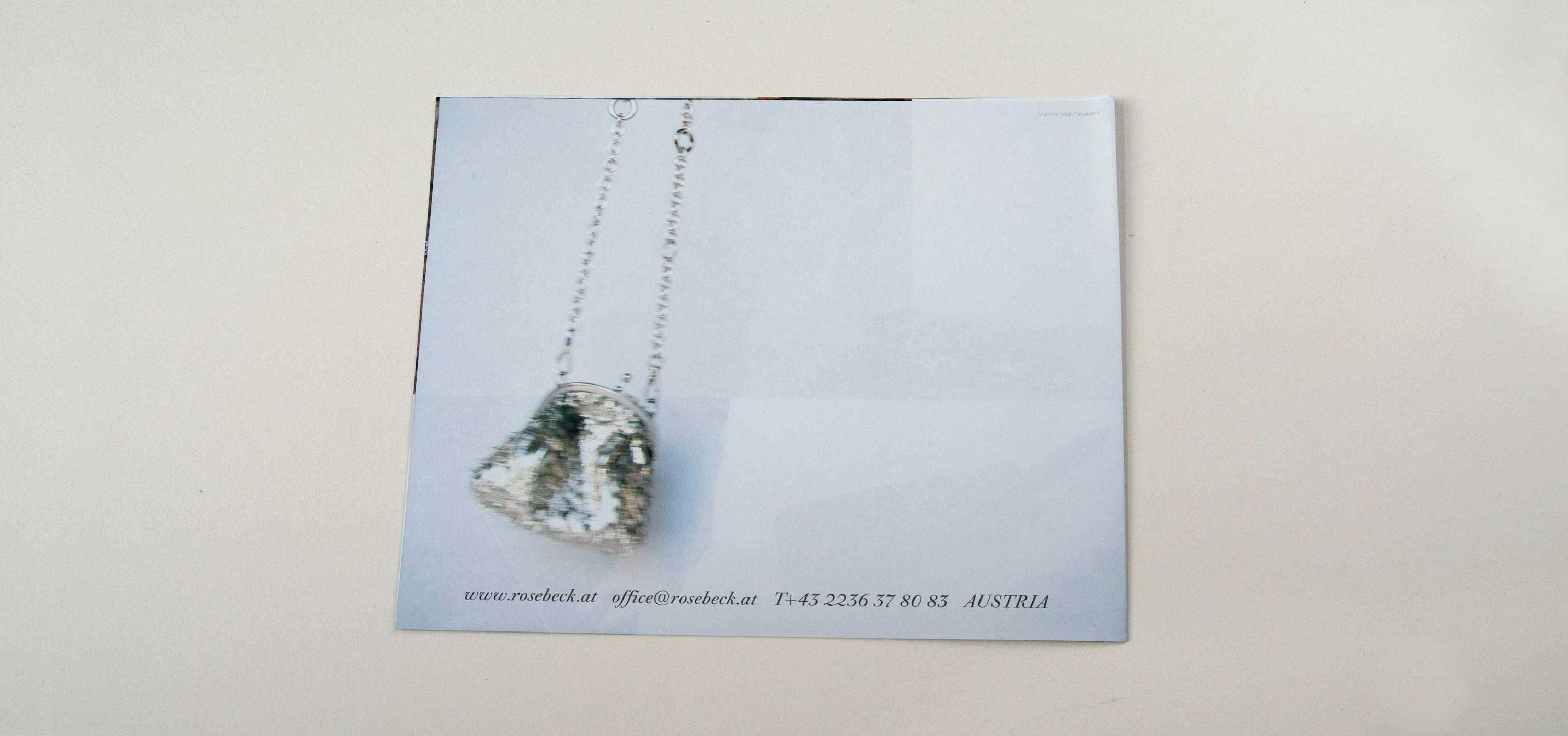 Back catalogue. Blurry full-page photo of pouch hanging on chain. Row of text overlayed at bottom.
