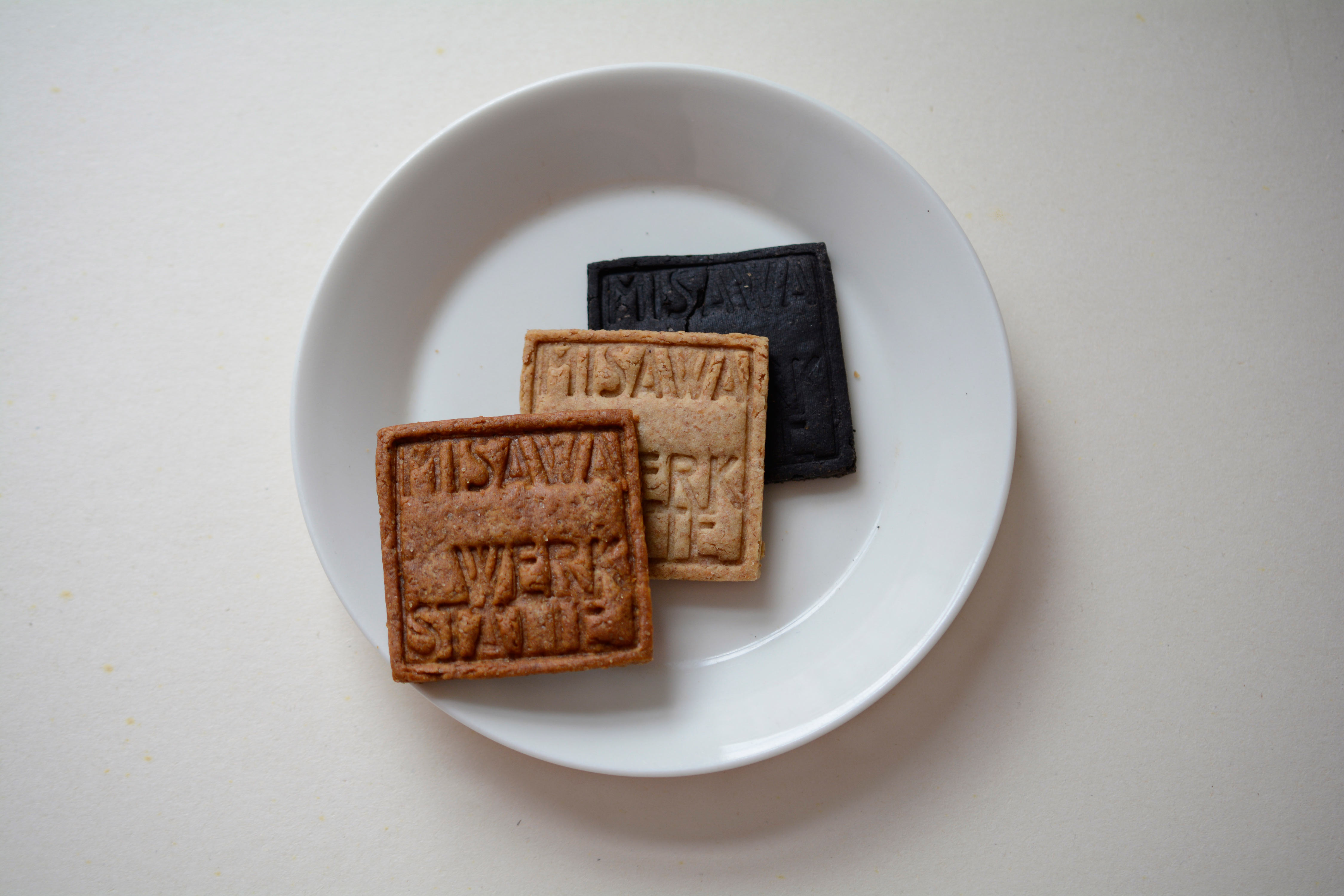 3 different coloured cookies on white plate. Punched logo on each cookie.