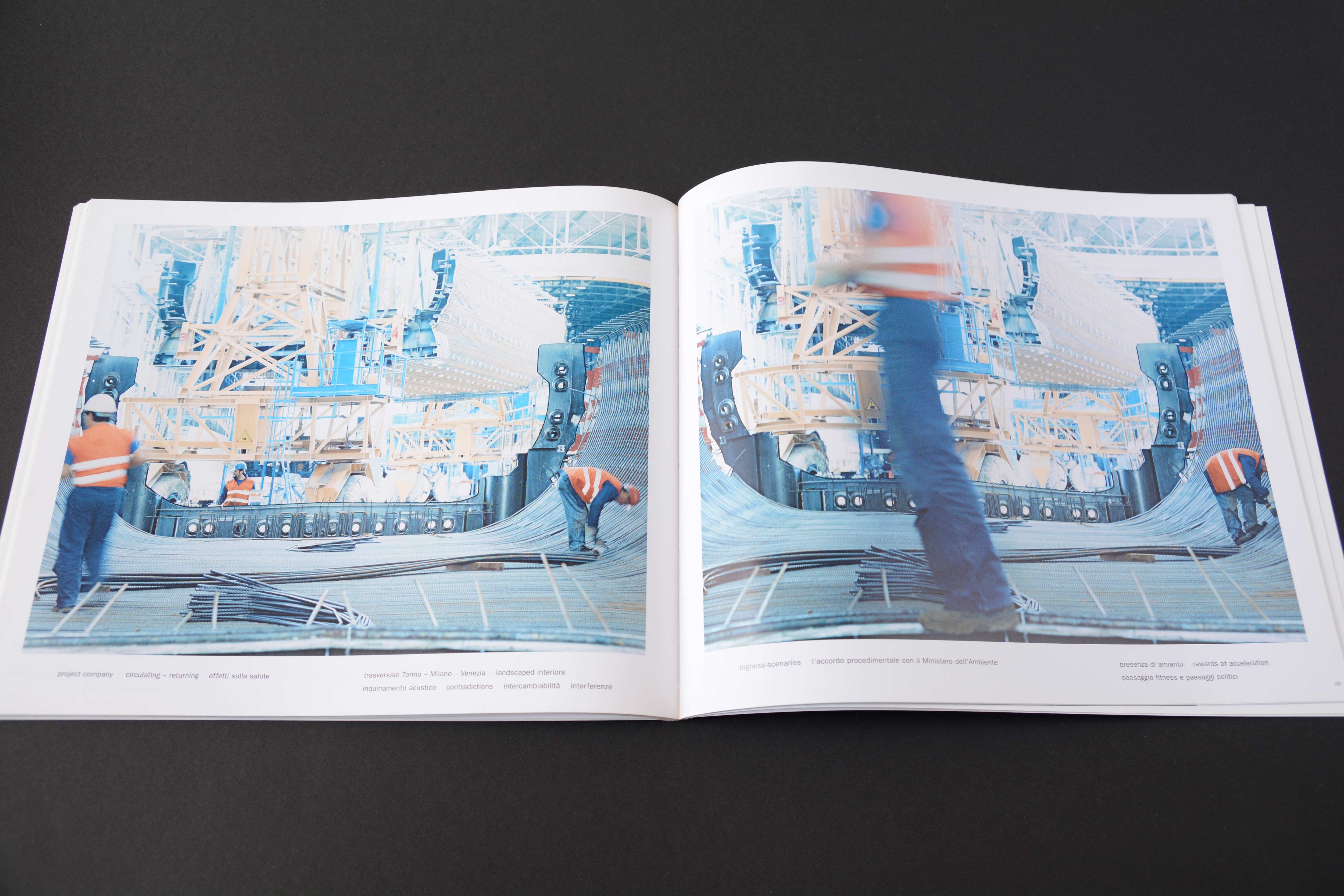 Double page. Large photo with white space around on each page. View into skeleton of bridge in contruction. Workers around. Lines of small text at bottom.