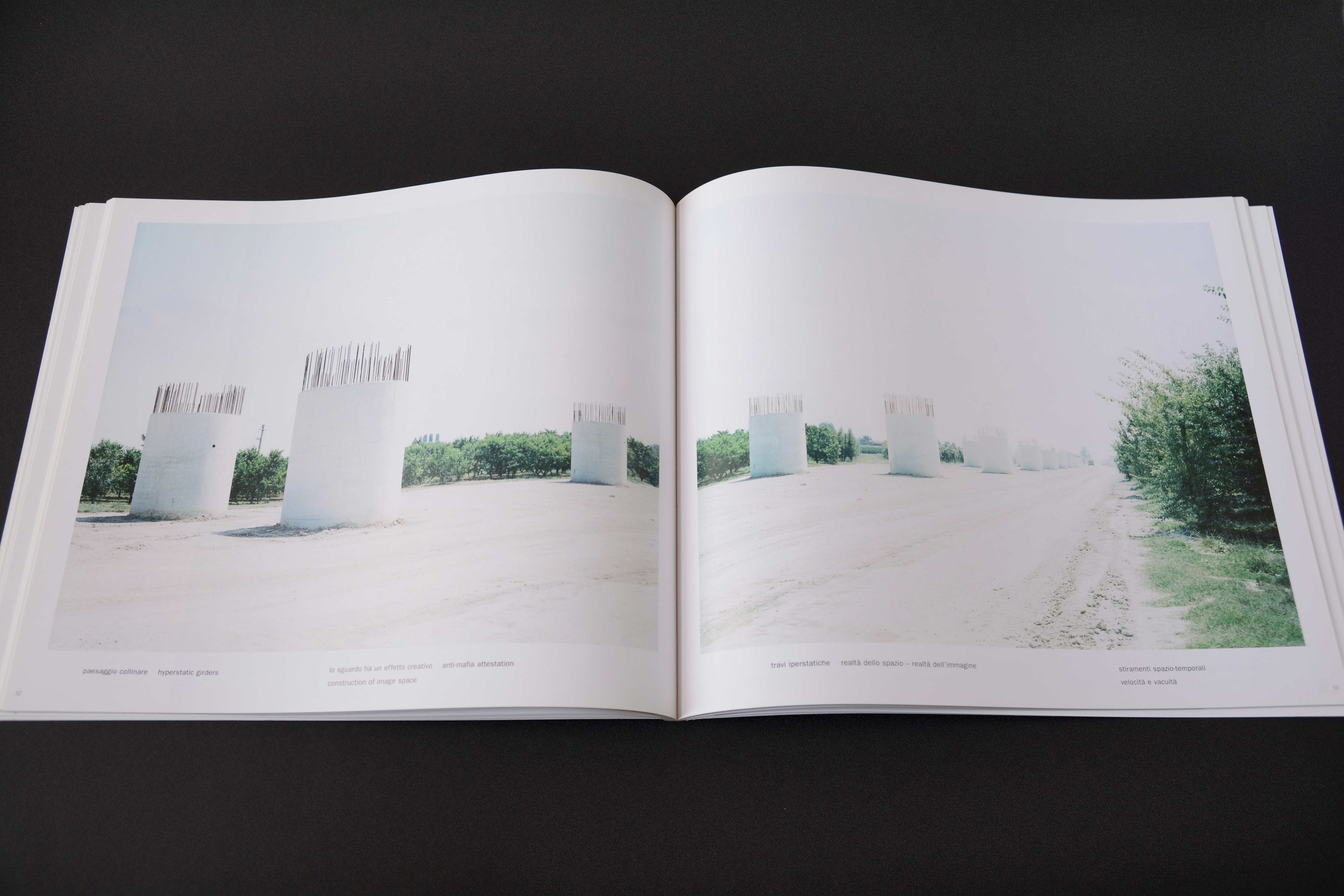 Double page. Large photo with white space around on each page. Row of large pillars only on flattened terrain. Lines of small text at bottom.