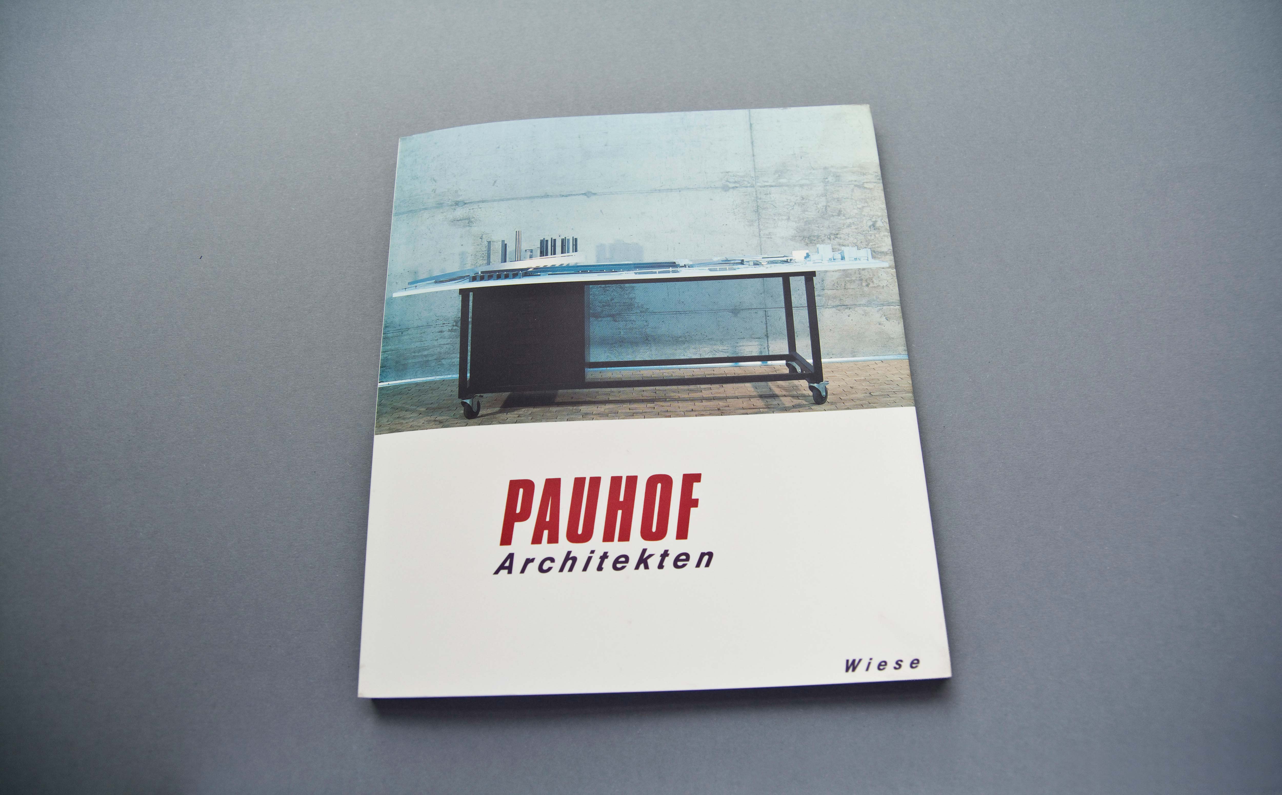 Cover Catalogue. Upper half: Full-page photo of architectural model on desktop. Lower half: White space with large Title.