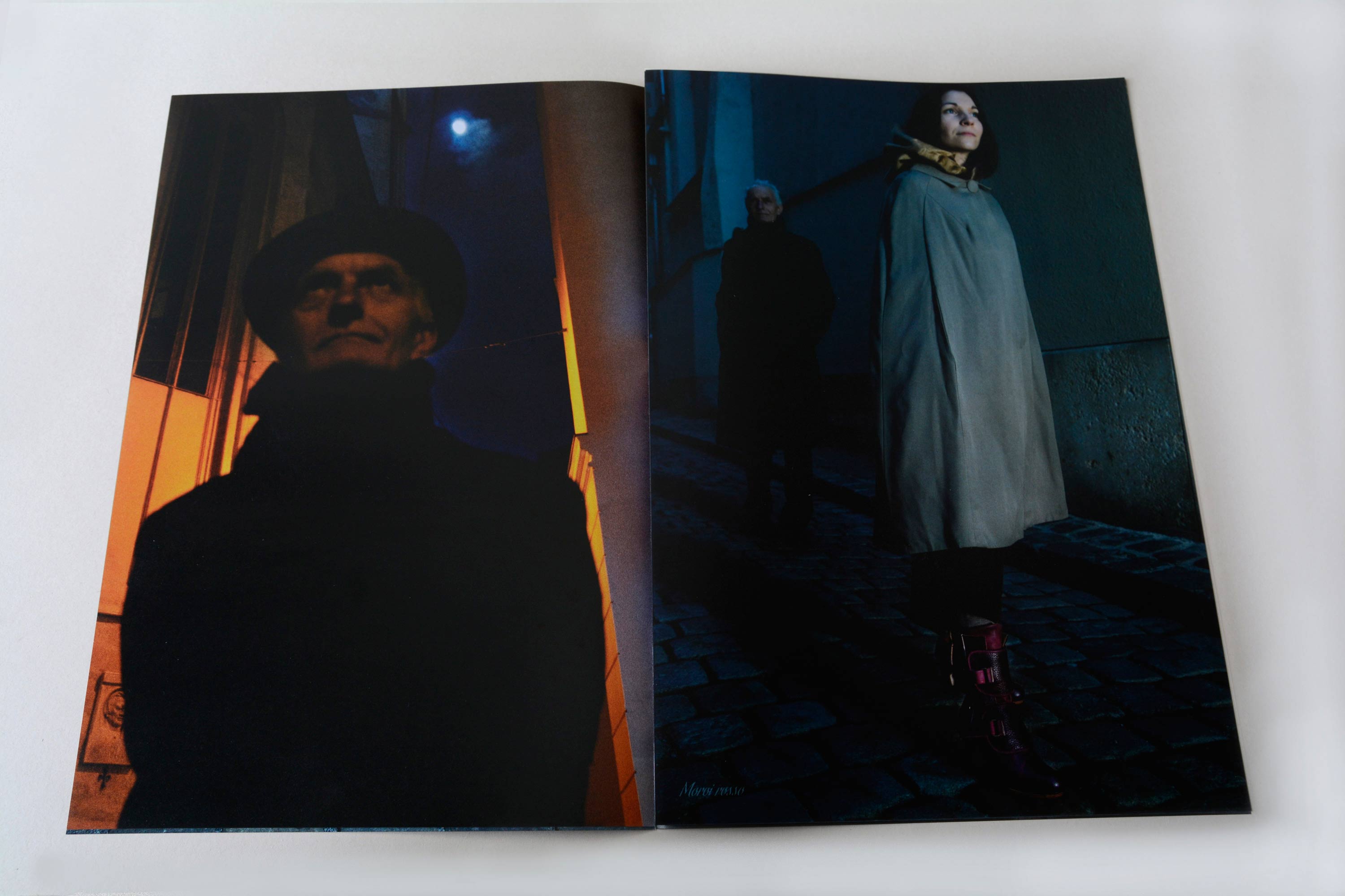 Double page showing full-page night shots. Small script font overlayed at bottom. Left page: Close up of man with moon in the background. Right page: Couple standing on a coblestone street.