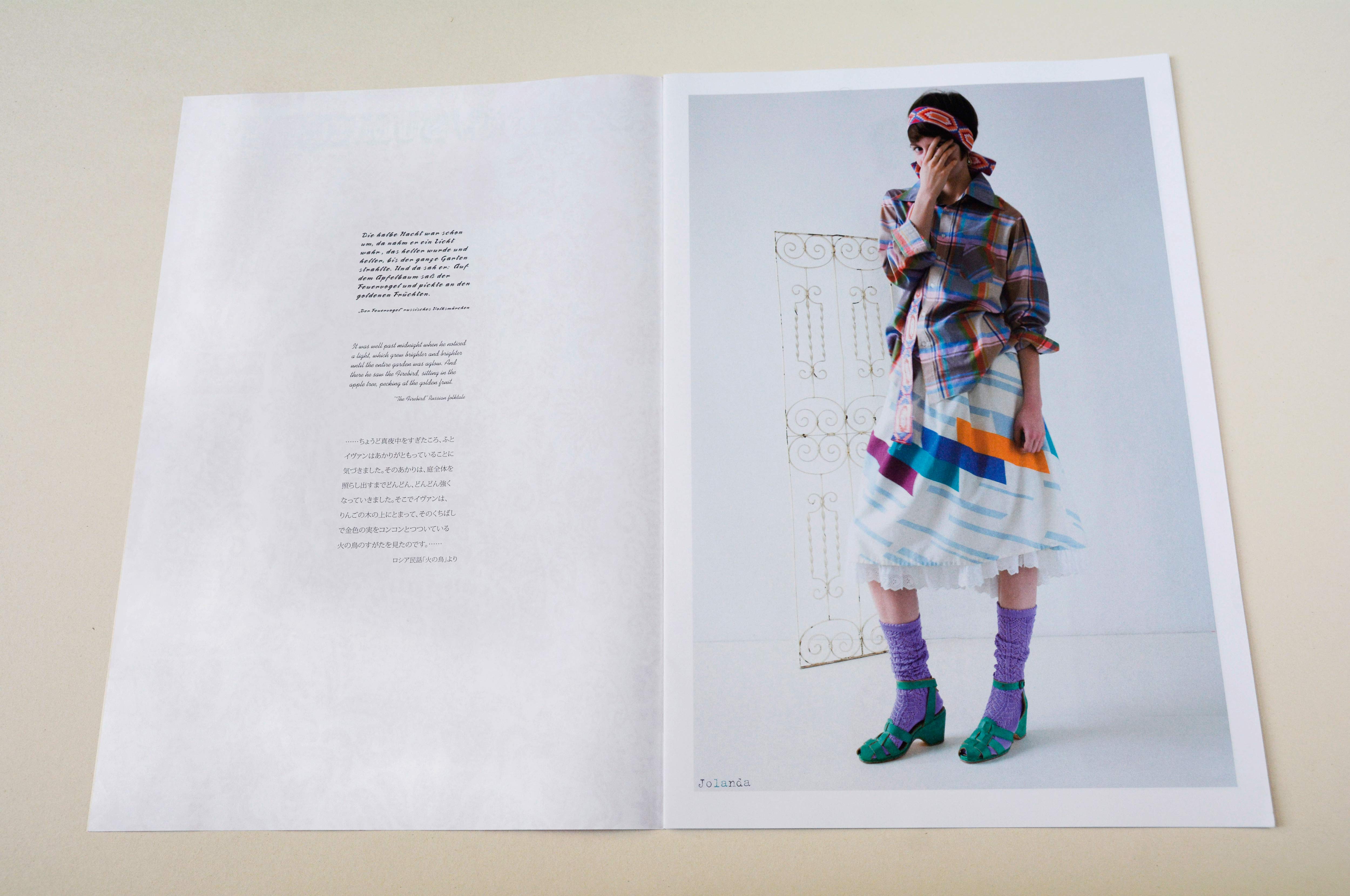 Double page. Left: Small block of text in various fonts and languages. Right: Large photo of woman standing in front of neutral background. Part of an iron door beside her. Small font overlayed at bottom.