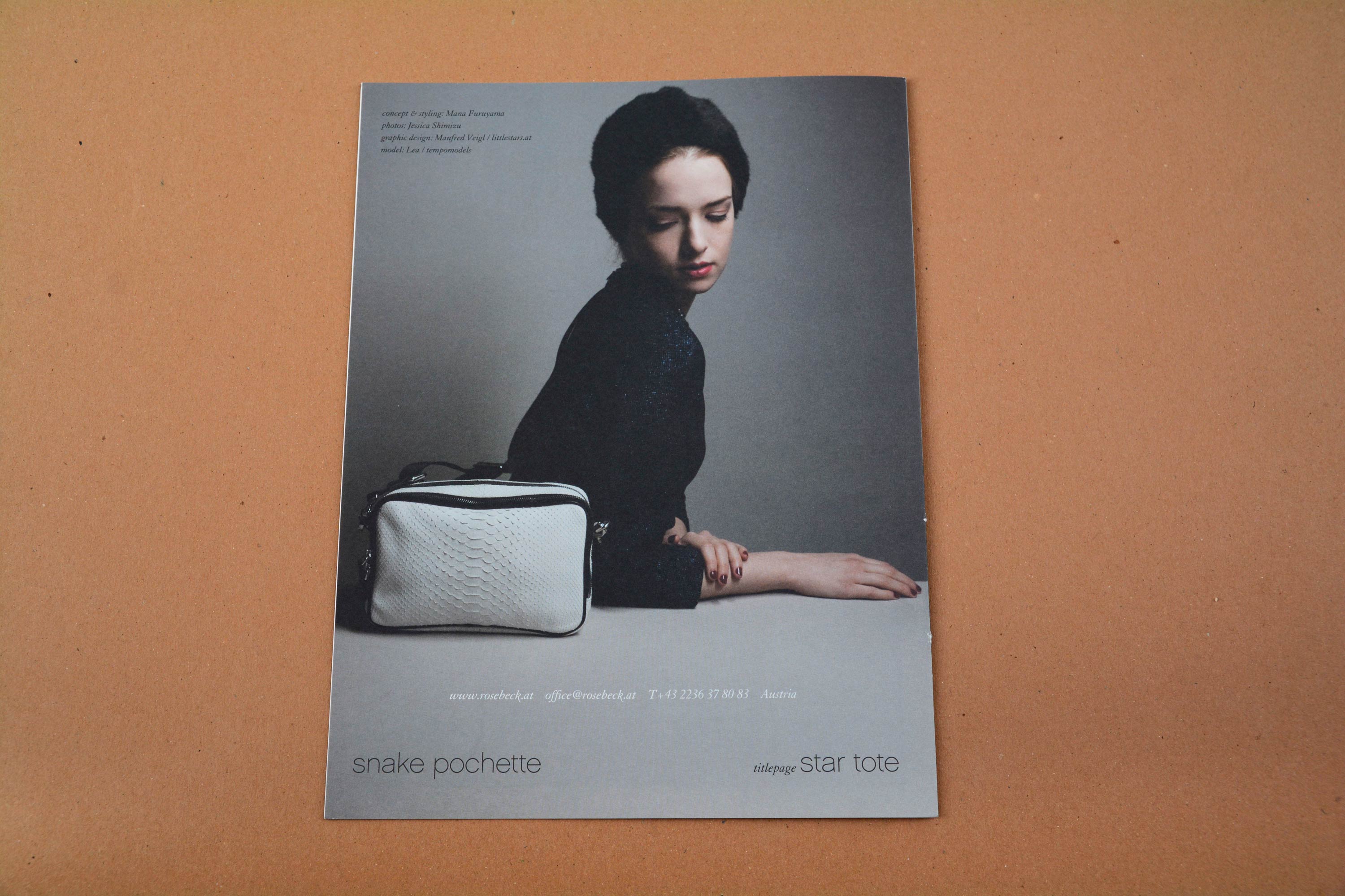 Back catalogue. Full-page photo of samll handbang standing on white table. Woman sitting behind looking at it. Small blocks of text overlayed on top and bottom.