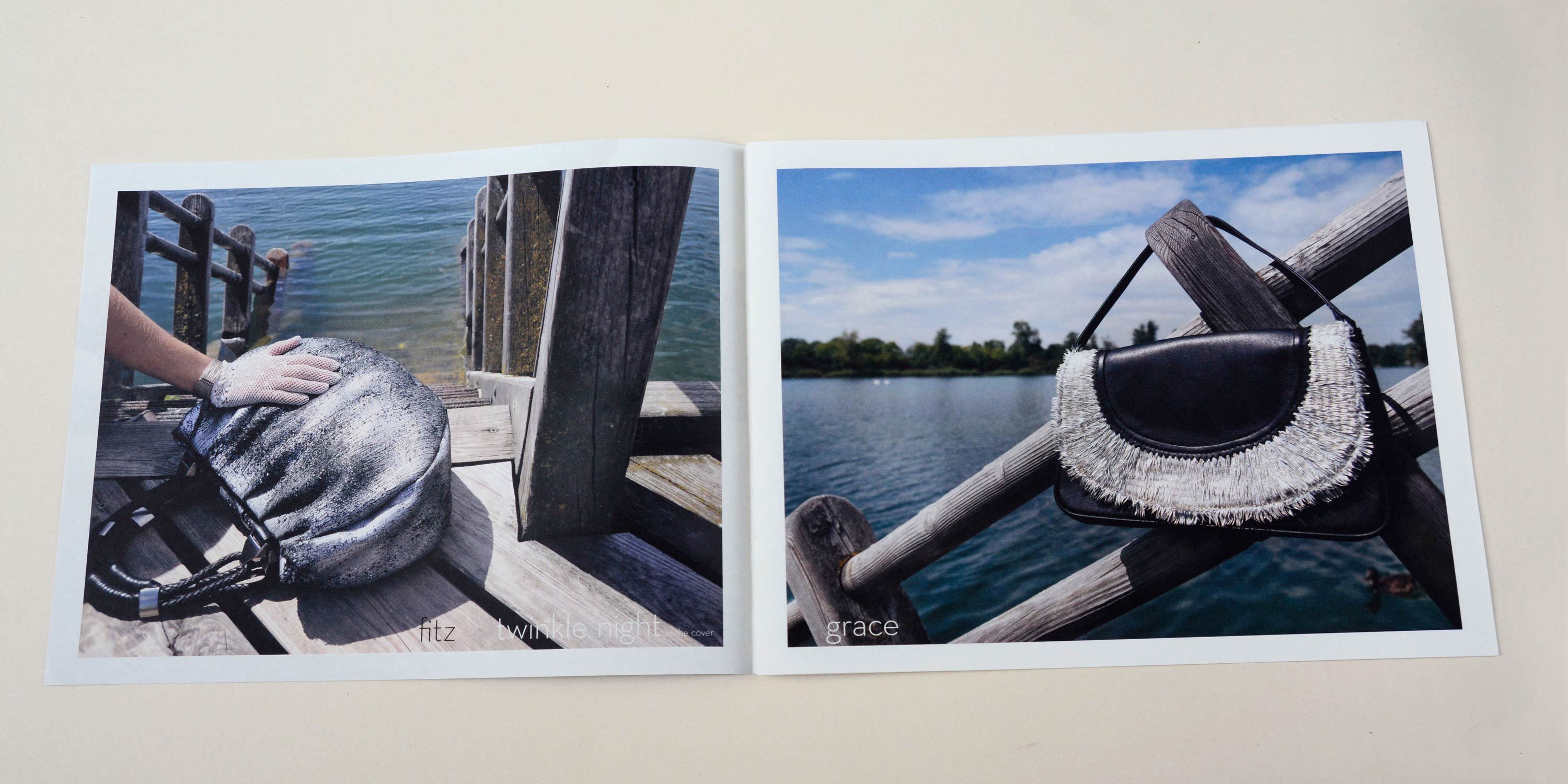 Double page. Full-page photo with white-space around. Thin font at botto overlayed. Left: Handbag lies on wooden bridge. Water in the background. Hand lies on the bag. Right: Handbag hangs on wooden railing. Water in the background.