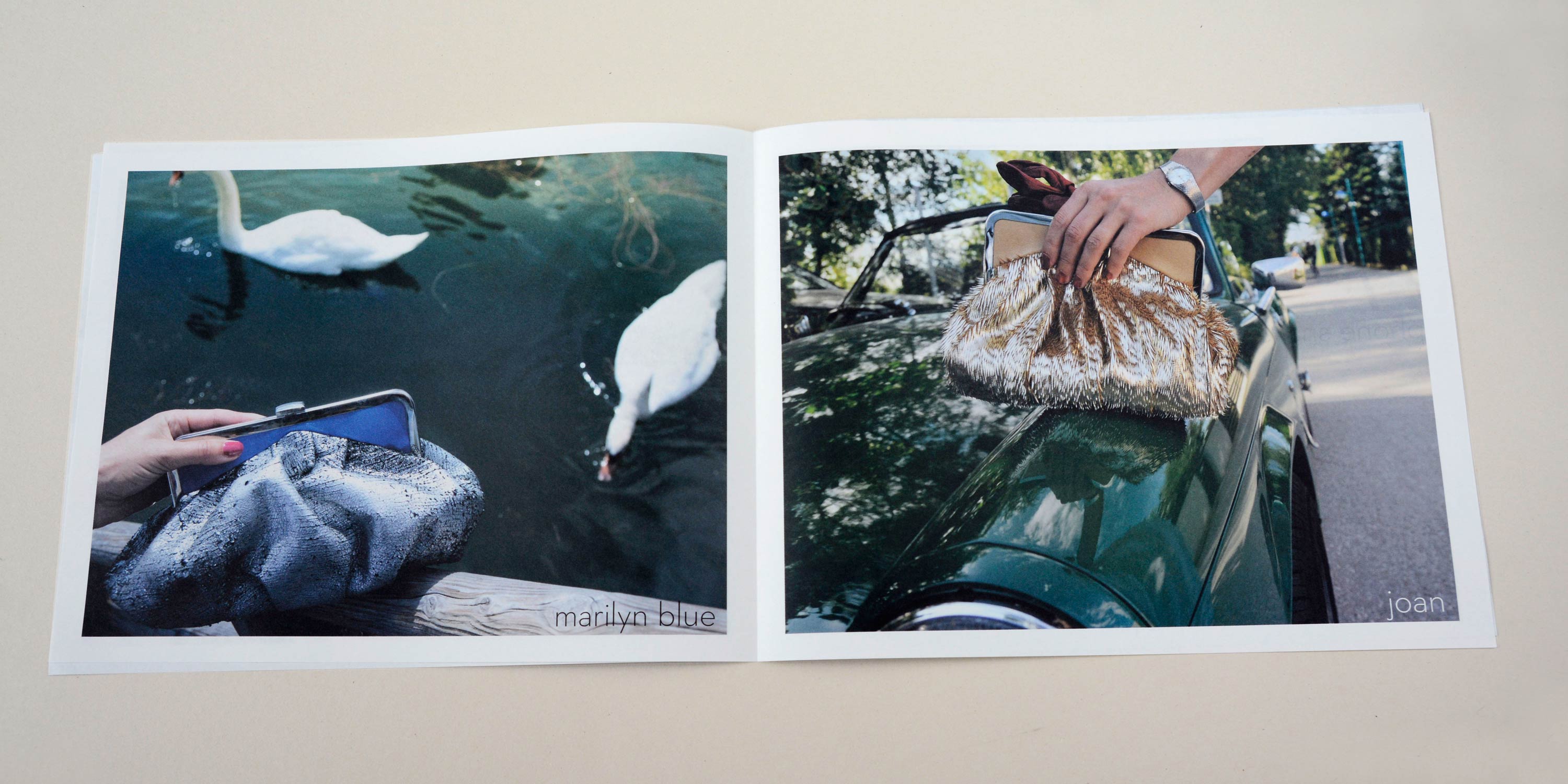 Double page. Full-page photo with white-space around. Thin font at botto overlayed. Left: Hand holds handbag over wooden railing. Swans swimming in water in the background. Right: Hand holds Handbag over bonnet of old elegant car.