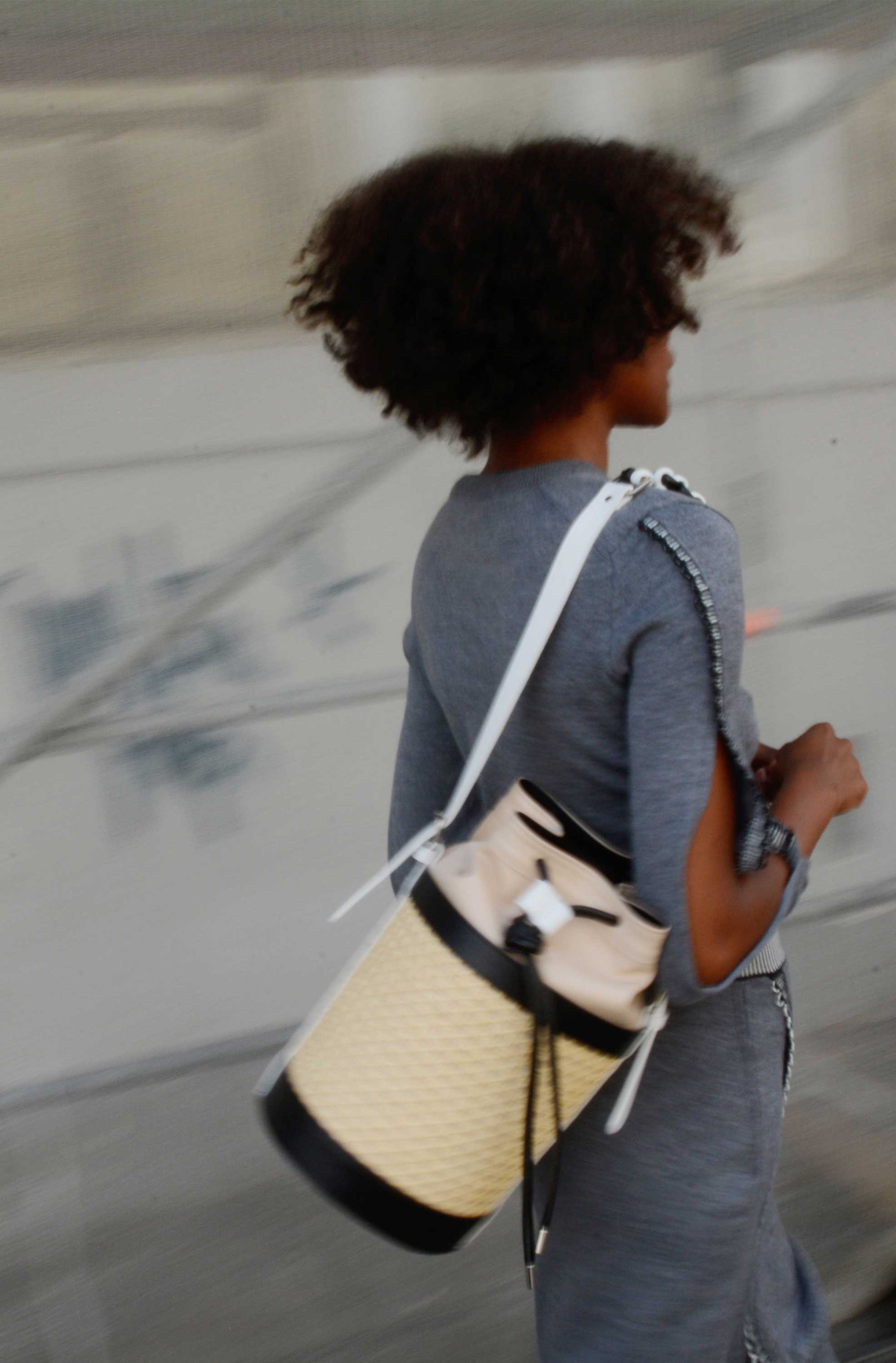 Woman moving on the street. Carries handbag around her shoulder.